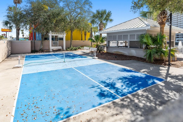 exterior space featuring a tennis court, fence, and a pergola