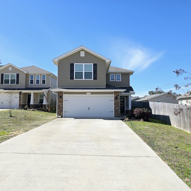 view of front of home featuring concrete driveway, an attached garage, fence, stone siding, and a front lawn