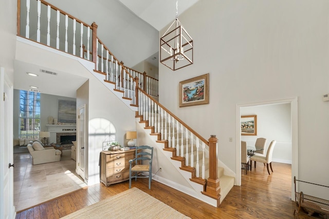 stairs featuring a towering ceiling, wood finished floors, visible vents, and baseboards