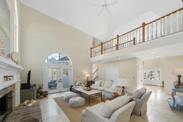 living room featuring french doors, light tile patterned floors, a fireplace, and stairs