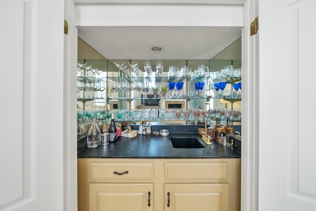 bar featuring a textured ceiling, a sink, and wet bar