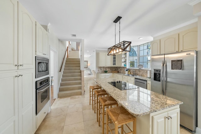 kitchen with hanging light fixtures, backsplash, appliances with stainless steel finishes, a kitchen island, and light stone countertops