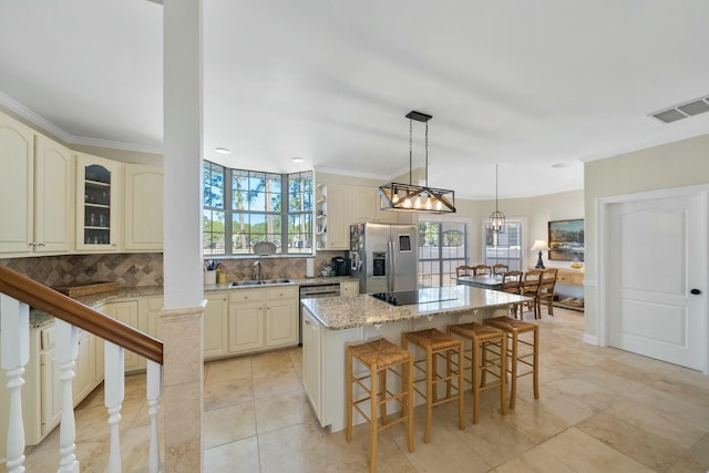 kitchen featuring cream cabinetry, visible vents, appliances with stainless steel finishes, glass insert cabinets, and a kitchen island