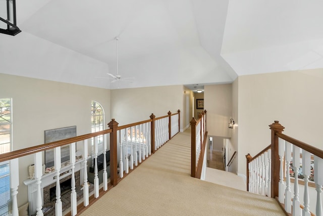 hallway featuring light colored carpet, vaulted ceiling, and an upstairs landing