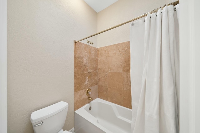 bathroom featuring a textured wall, shower / bath combination with curtain, and toilet