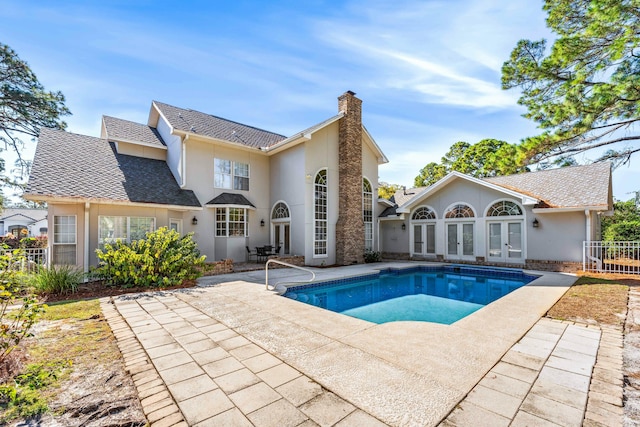 pool with french doors, a patio area, and fence