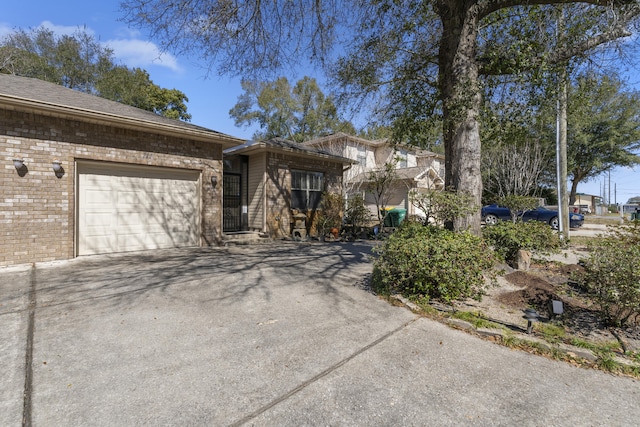 view of front facade with a garage, driveway, and brick siding