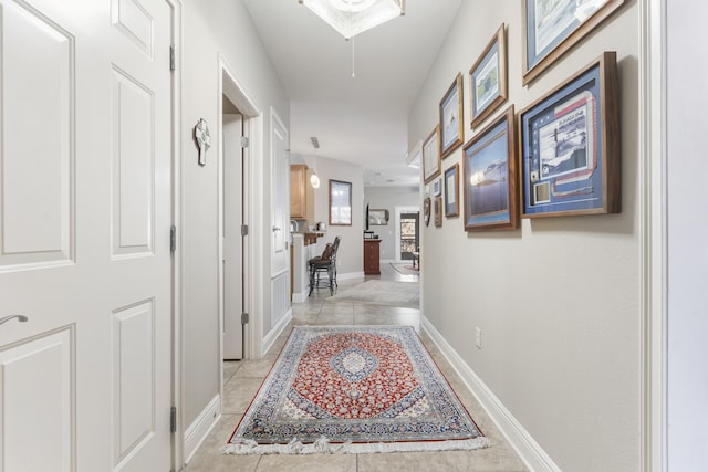 hallway with light tile patterned flooring and baseboards