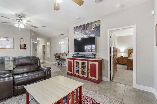 living room with light tile patterned floors, ceiling fan, visible vents, and baseboards