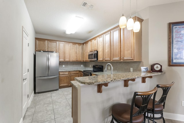 kitchen featuring a breakfast bar, light tile patterned floors, tasteful backsplash, appliances with stainless steel finishes, and a peninsula