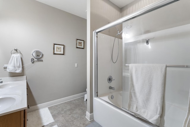 full bath with double vanity, baseboards, tile patterned flooring, combined bath / shower with glass door, and a sink