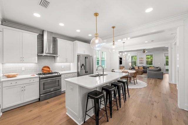 kitchen with wall chimney range hood, white cabinetry, appliances with stainless steel finishes, and light countertops