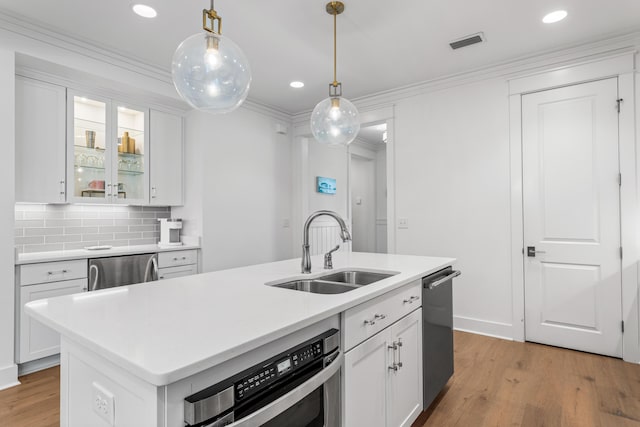 kitchen featuring a center island with sink, white cabinets, a sink, and light countertops