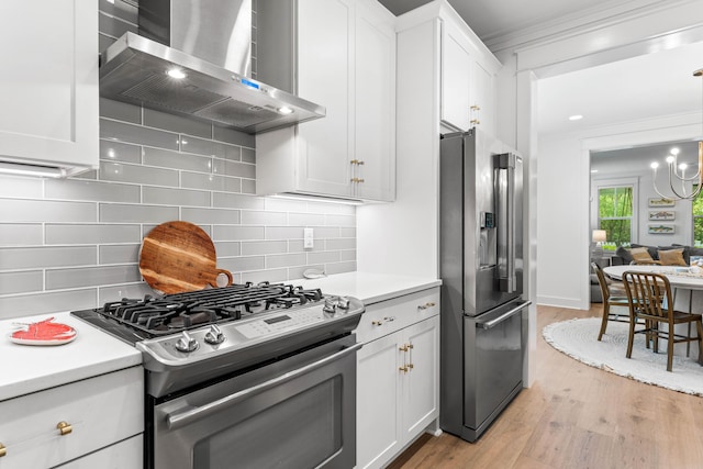 kitchen with white cabinets, light countertops, appliances with stainless steel finishes, range hood, and light wood finished floors