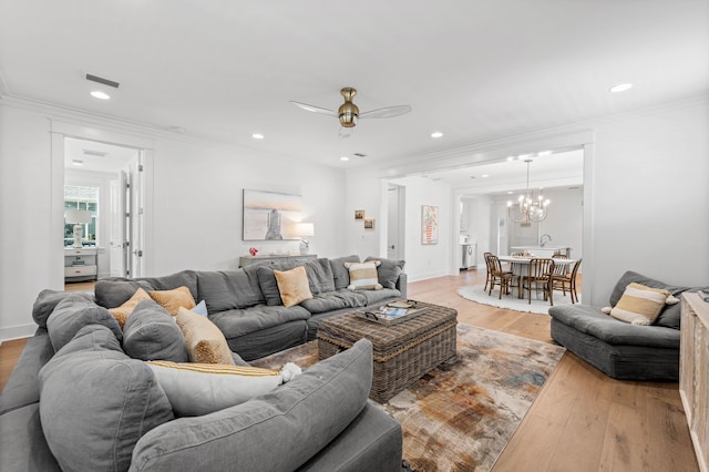 living room with light wood-style floors, visible vents, and crown molding