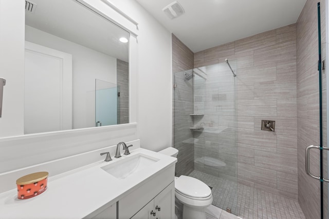 bathroom with a stall shower, visible vents, vanity, and toilet