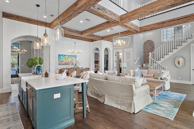 living area featuring a chandelier, arched walkways, dark wood-style floors, and beam ceiling