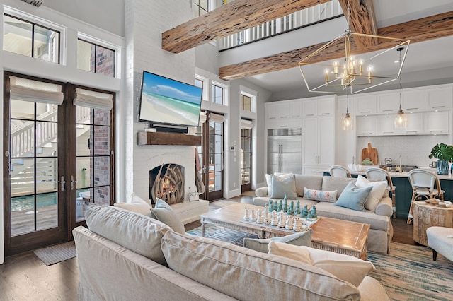 living area featuring a chandelier, a fireplace, a towering ceiling, and light wood-style floors