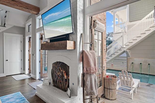 living room with a fireplace, beam ceiling, and wood finished floors