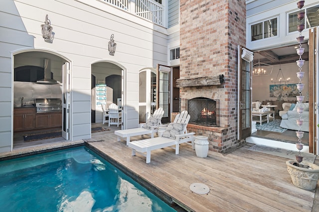 view of swimming pool with a sink, a fireplace, a grill, and a wooden deck