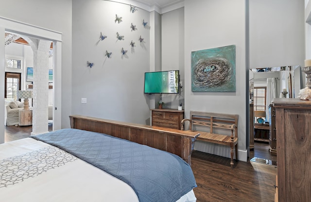 bedroom with dark wood-style floors and arched walkways