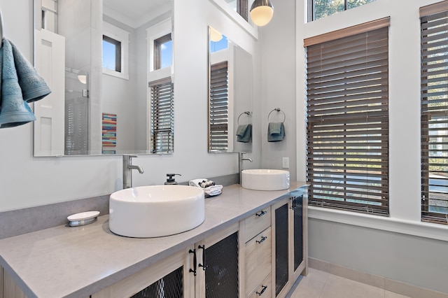 full bathroom featuring double vanity, tile patterned flooring, baseboards, and a sink