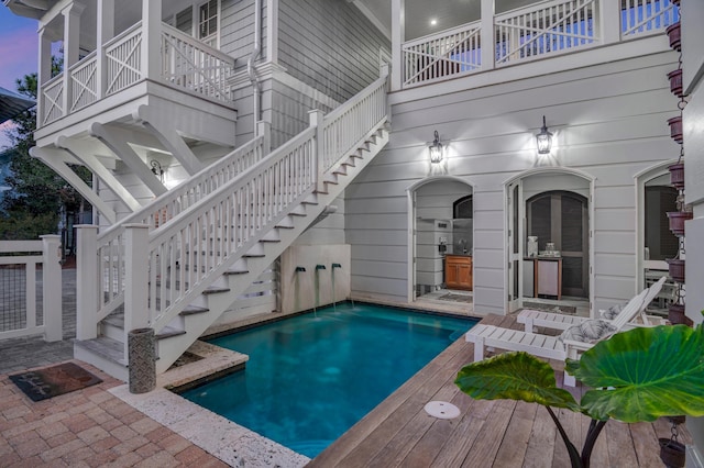 outdoor pool with stairway and a patio