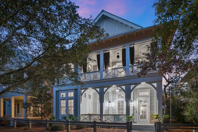 view of front facade featuring a balcony, covered porch, and a fenced front yard