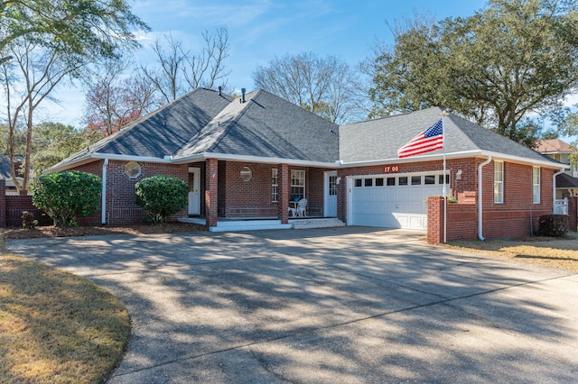 single story home with covered porch, a garage, a shingled roof, brick siding, and concrete driveway