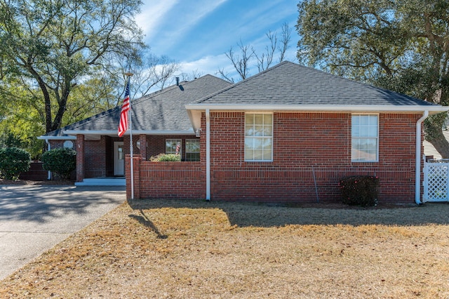 view of front of home with driveway, brick siding, and a shingled roof