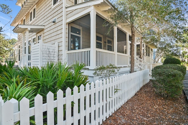 view of side of property with a fenced front yard and a sunroom