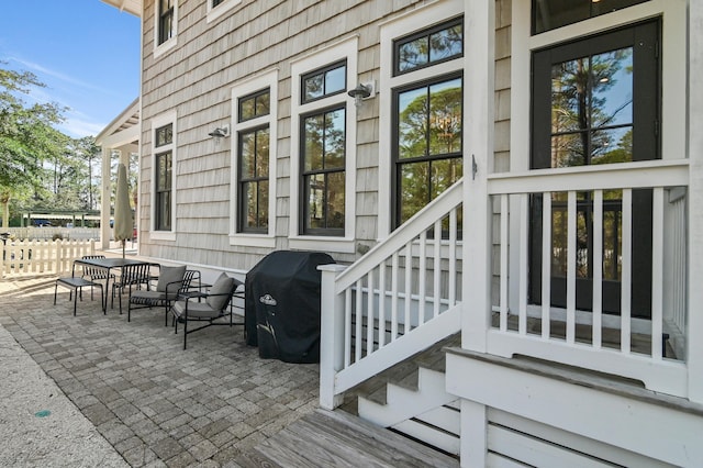 view of exterior entry with a patio area, fence, and outdoor dining space