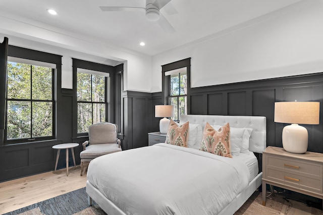 bedroom with a wainscoted wall, light wood finished floors, recessed lighting, a decorative wall, and ceiling fan