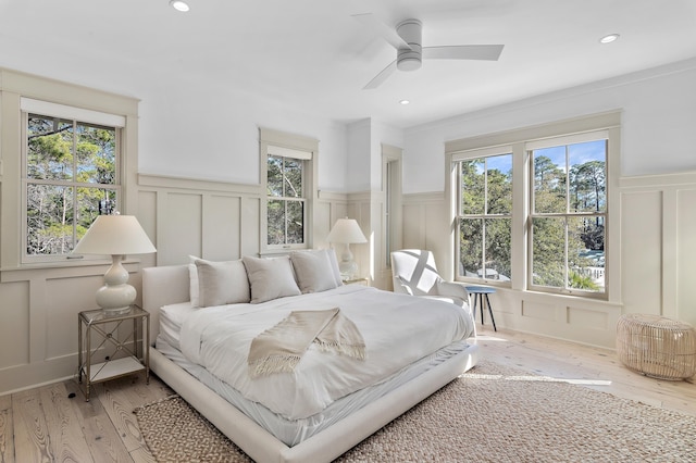 bedroom featuring recessed lighting, multiple windows, a decorative wall, and light wood finished floors