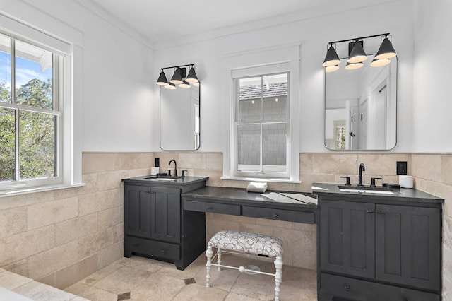 bathroom featuring a wealth of natural light, wainscoting, tile walls, and vanity