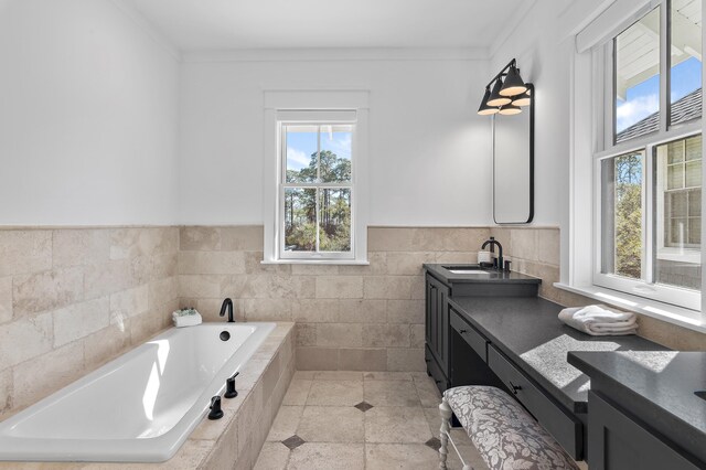 full bath with tile patterned flooring, a garden tub, vanity, tile walls, and ornamental molding