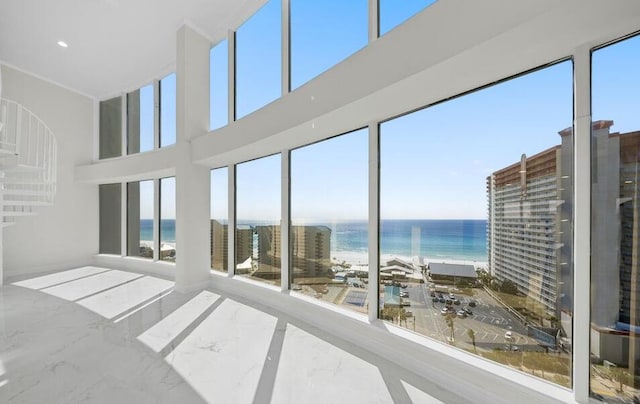 unfurnished sunroom featuring a water view and a view of the beach