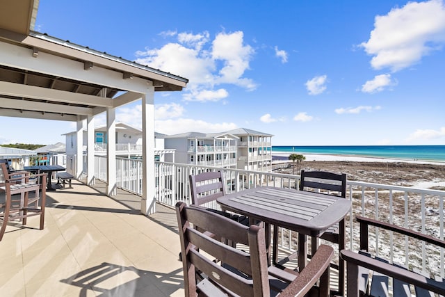 balcony with a water view, a patio area, and a view of the beach