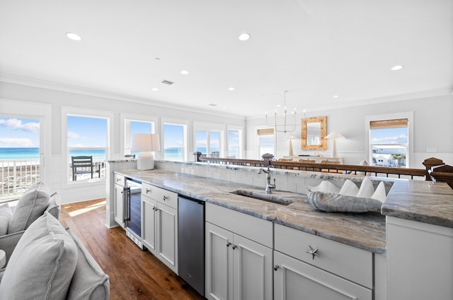 kitchen featuring light stone counters, crown molding, a water view, open floor plan, and a sink