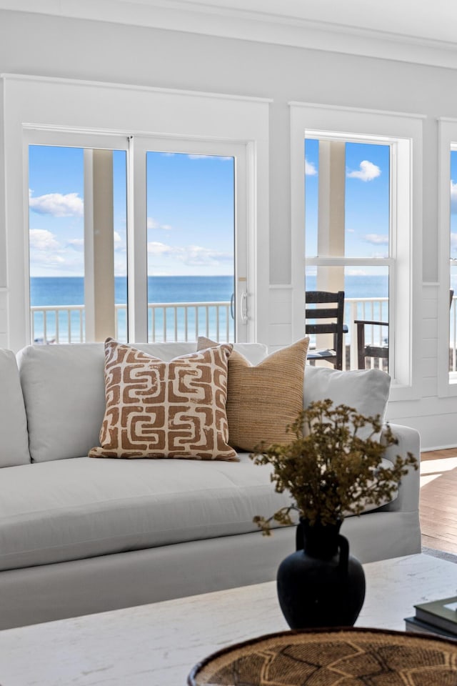 living room with a water view, crown molding, and wood finished floors