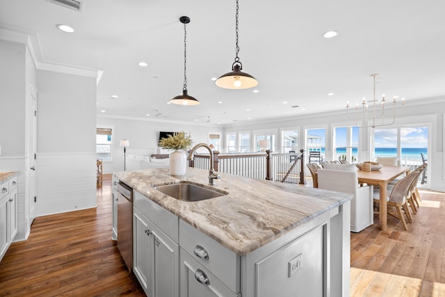 kitchen with an island with sink, open floor plan, decorative light fixtures, stainless steel dishwasher, and a sink