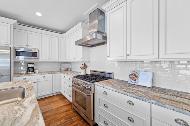 kitchen featuring light wood-style flooring, stainless steel appliances, a sink, white cabinetry, and range hood