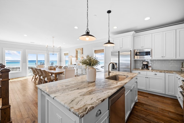 kitchen with a water view, a kitchen island with sink, appliances with stainless steel finishes, and open floor plan