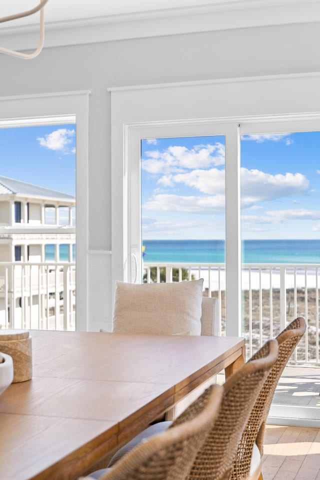 unfurnished dining area featuring a water view, a view of the beach, and wood finished floors