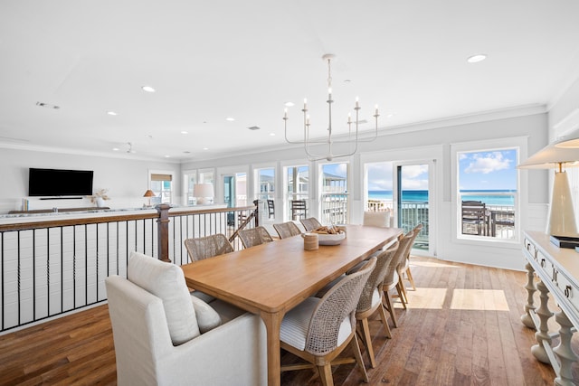 dining space featuring a water view, light wood-type flooring, visible vents, and crown molding