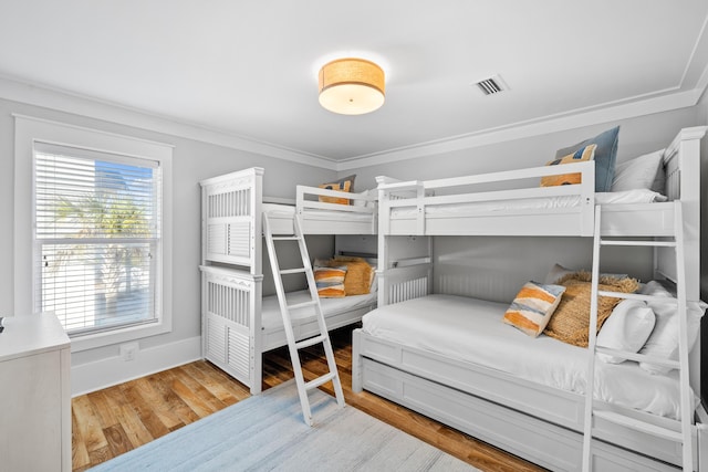 bedroom with visible vents, crown molding, light wood-style flooring, and baseboards