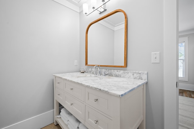 bathroom featuring baseboards, crown molding, and vanity