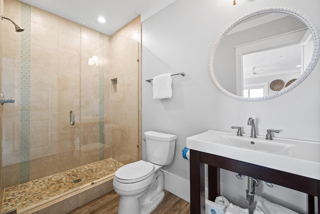 bathroom with a shower stall, toilet, and wood finished floors