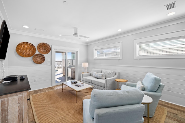 living area with dark wood-style floors, visible vents, crown molding, and wainscoting