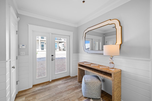 doorway featuring ornamental molding, wainscoting, and light wood-style flooring